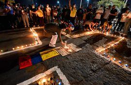 People place lit candles on the ground during a vigil on May 5, 2021 in Cali, Colombia, in honor of the demonstrators who died during protests against the government of President Ivan Duque. - Thousands of people returned to the streets of Colombia on May 5 in rejection of the government of Ivan Duque, who has completed a week of pressure with demonstrations that turned violent in some cities and left some twenty people dead. (Photo by Luis ROBAYO / AFP)