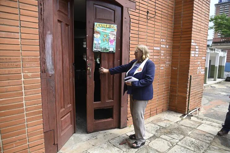 La licenciada Mirtha Aquino Amarilla exhibe una puerta de la institución, que fue destrozada por los ladrones.