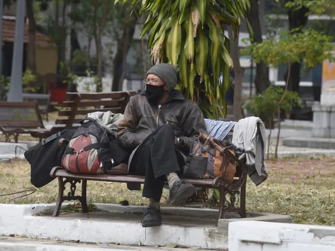 Hombre abrigado para el ingreso del frente frío sentado en una plaza de Asunción. (Archivo).