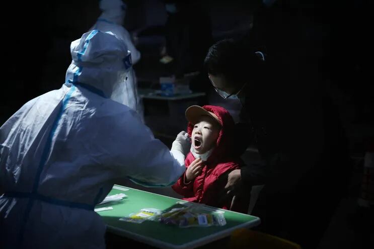 Un miembro del personal sanitario toma una muestra a un niño, para verificar si tiene coronavirus, en el distro de Ganzhou, en China.