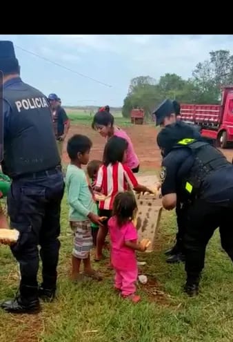 Agentes policiales ayudan a niños indígenas a cargar sus pertenencias para salir de la propiedad ocupada, en Itakyry