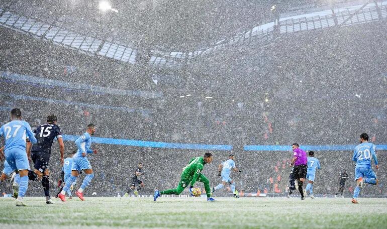 El arquero Ederson, del Manchester City, sale jugando con un compañero en el campo del estadio Etihad, que estaba cubierto por nieve.