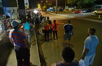 Pasajeros esperan colectivo en los alrededores de la Terminal de Ómnibus de Asunción, para retornar al hogar, durante una noche de regulada del transporte público.