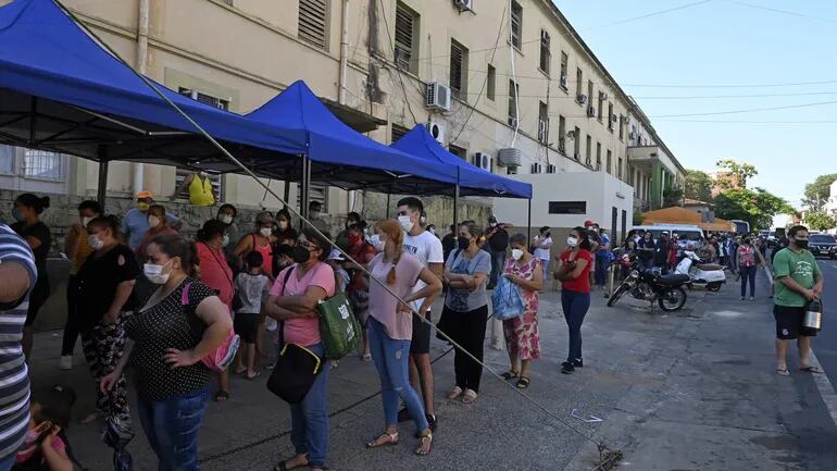 Varias personas esperan en fila para realizarse una prueba de covid-19 en la sede del Ministerio de Salud en el microcentro de Asunción, este sábado.