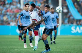El paraguayo Adam Bareiro, futbolista de San Lorenzo de Almagro, pelean por el balón en un partido frente a Belgrano por la Copa de la Liga de Argentina.