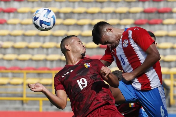 Víctor Sebastián Quintana (de Olimpia) en una dura puja aérea por la pelota ante una fuerte marca del venezolano Alcócer. (EFE)