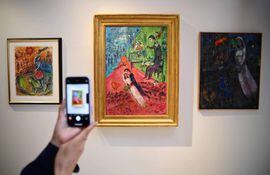 Una mujer toma una fotografía de una obra del artista Marc Chagall, durante una presentación en Christie's en París.