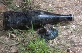 Una de las botellas presuntamente cargadas con algún combustible que encontraron cerca del vehículo incendiado en una playa de autos en Fernando de la Mora.