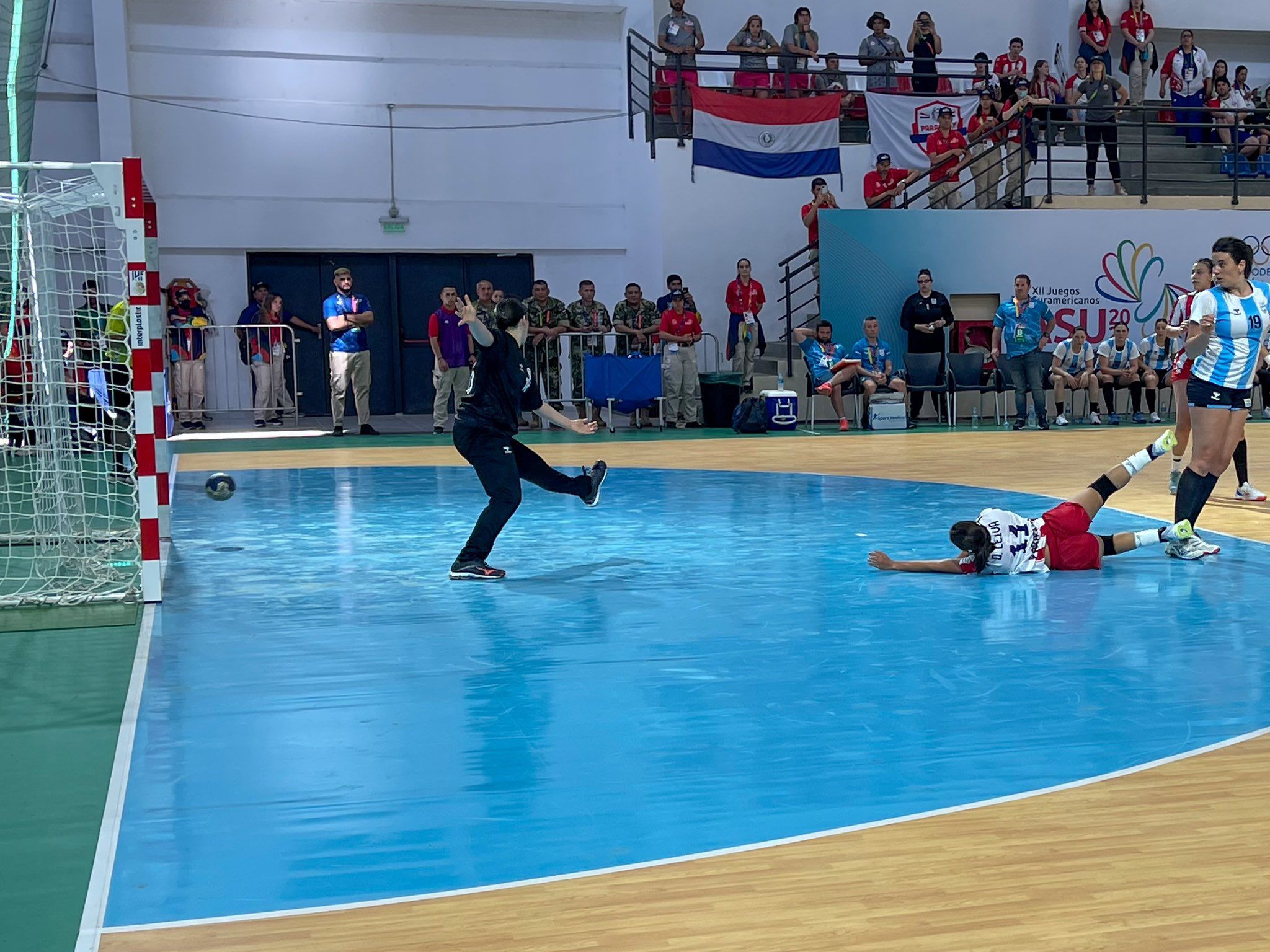 Esther Leiva cae el piso tras la marca de la defensa argentina, pero consigue anotar un gol en la victoria de Paraguay ante Argentina en el handball femenino de los Juegos Odesur Asunción 2022.