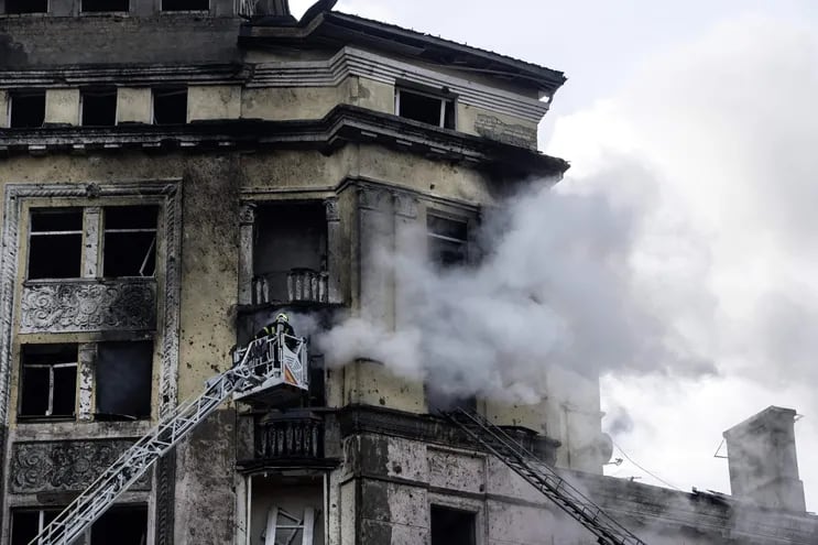 Bomberos ucranianos extinguen el fuego de un edificio destrozado por un misil ruso.