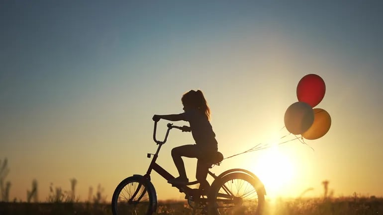 Una niña pedalea su bicicleta al atardecer.
