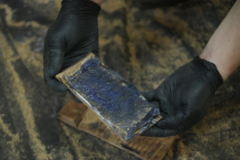 Uno de los investigadores exhibe cómo estaban pegadas las pequeñas láminas de droga a las maderas de kurupa'y. 