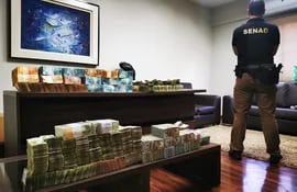 Un agente de la Senad custodia el dinero incautado el jueves en una casa de cambios en Asunción.