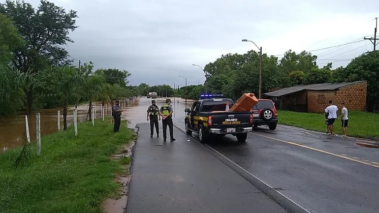 Agente policial, de la Patrulla Caminera y Bomberos Voluntarios trabajan para evitar que se cruce la calzada del arroyo Yaguarón.