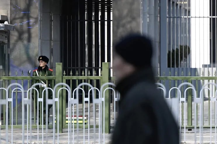 Un oficial de policía paramilitar chino (izq.) hace guardia frente a la embajada de Australia en Beijing el 5 de febrero de 2024. El gobierno de Australia dijo el 5 de febrero que el escritor Yang Jun había recibido una sentencia de muerte suspendida en China, describiéndola como una "noticia desgarradora".