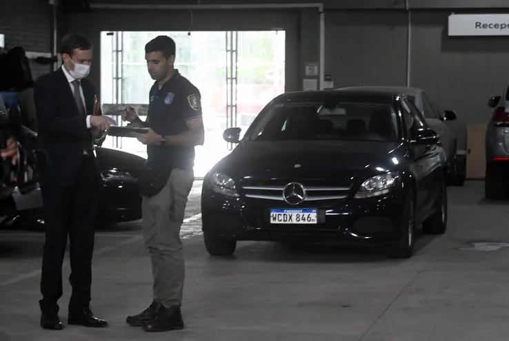 Agentes de la Fiscalía y de la Policía   retiran el auto Mercedes Benz del taller donde fue ubicado.