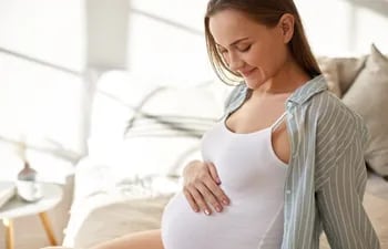 Embarazada observa su vientre con emoción.