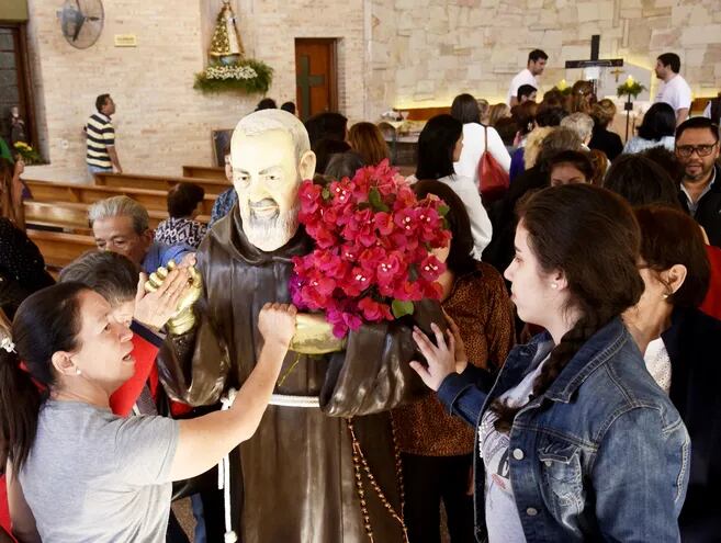Fieles tocan una de las imágenes de  San Pío de Pietrelcina en el templo capuchino de Trinidad, minutos antes de que se inicie  la misa. Cientos de creyentes se movilizaron para la celebración.