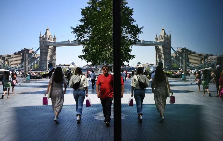Varias personas aparecen reflejadas en una ventana en las inmediaciones del Puente de la Torre, en Londres. Reino Unido continúa con su programa de vacunación en su lucha contra la variante india de la covid19 que continúa extendiéndose por el país. E