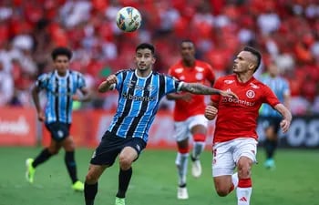 El paraguayo Mathías Villasanti (i), futbolista de Gremio, pelea por el balón en un partido del Estadual Gaúcho contra Internacional en el estadio Beira-Río, en Porto Alegre, Brasil.