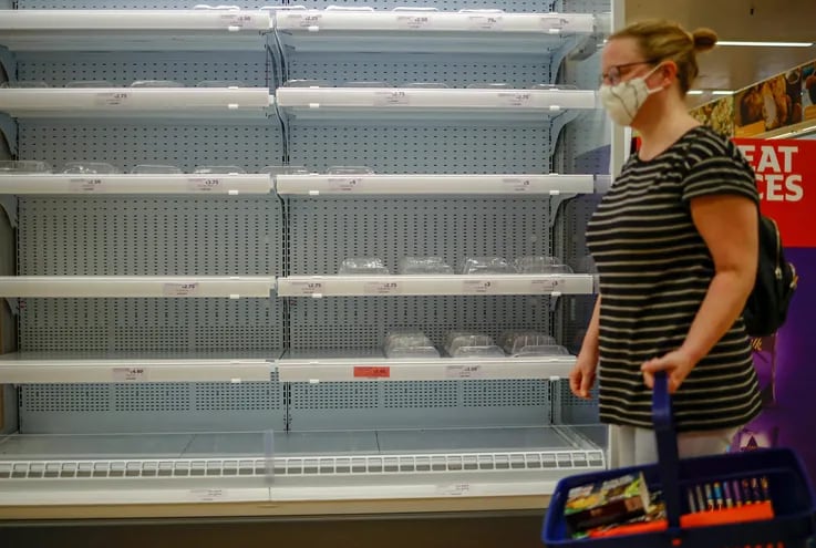 Una cliente camina junto a una góndola refrigerada semivacía en un local de la cadena de supermercados Sainsbury Walthamstow, east Londres.