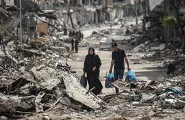 Dos personas caminan entre escombros de edificios destruidos en Jan Yunis, en el sur de la Franja de Gaza.