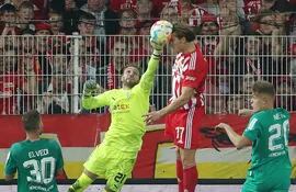 El delantero Kevin Behrens (d) cabecea el balón anticipándose al arquero arquero Tobías Sippel (i), del Borussia Moenchengladbach, y anota el empate parcial 1-1 para el Unión Berlín, que al final ganó 2-1 el partido.