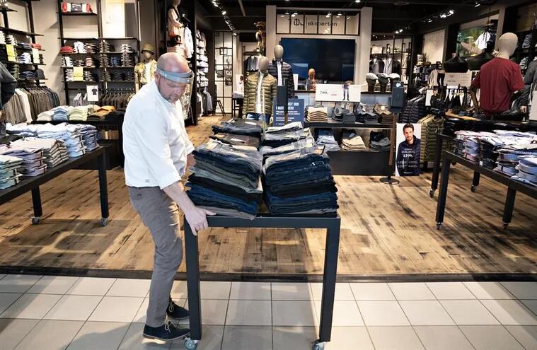 El empleado de una tienda de ropa en Aalborg, en Dinamarca, prepara el género ante de abrir al público, el pasado 21 de abril.