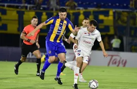 Rodrigo Rojas (i), volante del Sportivo Luqueño, y Mathías Martínez, de Nacional, pelean por el balón en el partido de la primera rueda del torneo Apertura 2023 del fútbol paraguayo en el estadio Defensores del Chaco, en Asunción.