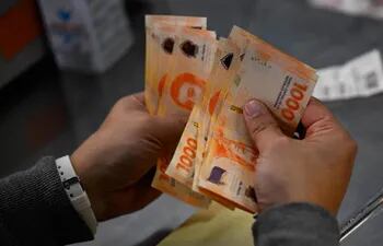 Un hombre cuenta mil billetes de pesos argentinos en Buenos Aires