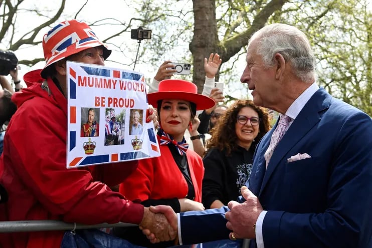 El rey Carlos III saluda a miembros del público reunidos esta mañana en la avenida The Mall, próxima al palacio de Buckingham y lee el cartel de una mujer que señala "Tu mami estaría orgullosa de vos", en alusión a la reina Isabel II.
