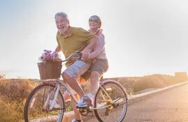 Una pareja de la tercera edad pasea en bicicleta.