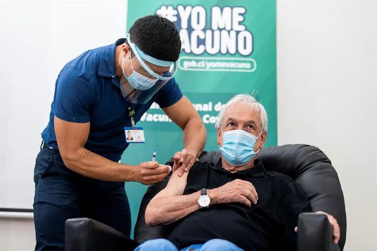 El presidente de Chile, Sebastián Piñera (c), mientras recibe la primera dosis de la vacuna contra la Covid-19 del laboratorio chino Sinovac.