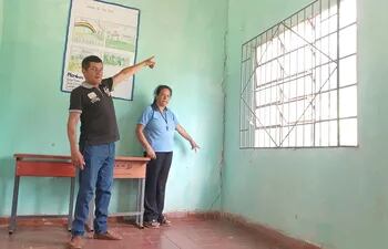 El padre de familia Ismael Ortega y la secretaria de la institución Norma Guillen mostrando las enormes grietas en las paredes.