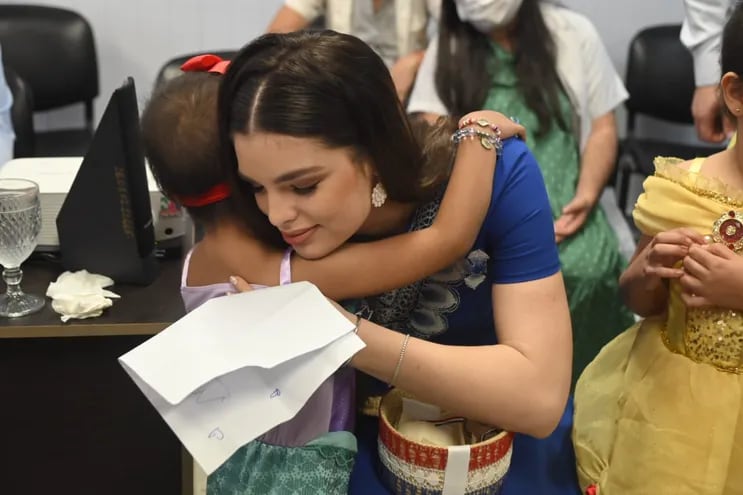 Nadia Ferreira recibiendo un tierno abrazo de una de las princesitas de la Fundación Renací.