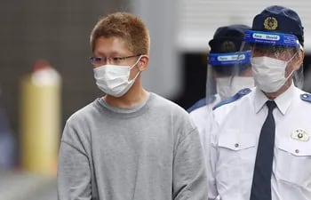 Kyota Hattori (izq.), sospechoso de 24 años de un ataque con cuchillo e incendio provocado en un tren de Tokio, es llevado ante la fiscalía bajo sospecha de intento de asesinato.