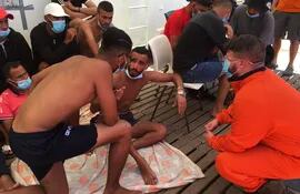 Un rescatista habla con migrantes en el barco "Ocean Viking", luego de que dos de ellos saltaran por la borda en el mar Mediterráneo y fueran rescatados.