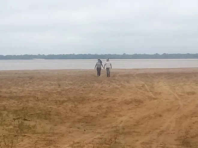 Una pareja de turistas se pasea por la playa punta arena de Itá Corá.