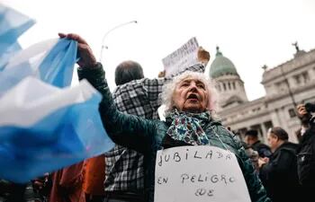 Una mujer sostiene una bandera de Argentina durante una movilización este lunes 29 de abril de 2024, en Buenos Aires (Argentina). En el Congreso argentino se realiza el debate del proyecto de la Ley Bases y Puntos de Partida para la Libertad de los Argentinos, más conocida como 'ley ómnibus', proyecto estrella del Ejecutivo de Javier Milei.