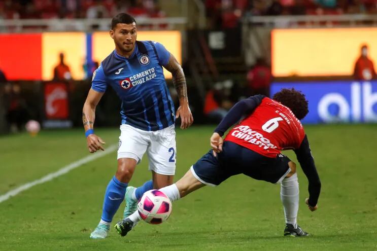 El paraguayo Juan Escobar, del Cruz Azul, intenta controlar el balón ante el mexicano César Huerta, de Chivas Guadalajara, durante el partido que disputaron Estadio Akron, en Guadalajara.