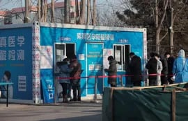 Personas con mascarillas forman fila para realizarse la prueba de la enfermedad covid-19 en el subdistrito de Shangdi en Haidian, Pekín, China. En la capital china, universitarios protestan contra las restricciones.