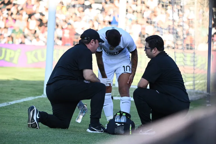 Derlis González (c), jugador de Olimpia, recibe la asistencia de los médicos del plantel a causa de una lesión en la rodilla izquierda durante el partido contra Libertad en el estadio Manuel Ferreira por la octava fecha del torneo Apertura 2023 del fútbol paraguayo.