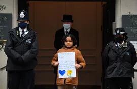 Una niña sostiene un cartel deseando pronta recuperación al príncipe Felipe del Reino Unido, ante las puertas del hospital donde se encuentra ingresado desde hace una semana.