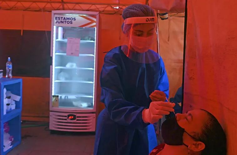 Una trabajadora de salud toma una muestra de una mujer para una prueba de covid-19 en Asunción, este sábado.