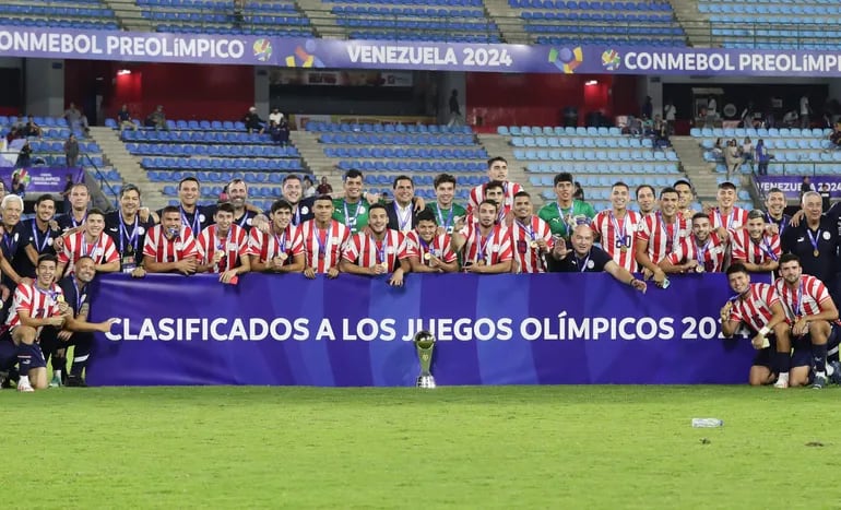 Los jugadores y cuerpo técnico de la selección paraguaya posan con el trofeo de campeón del Preolímpico 2024 y el cartel de clasificación a los Juegos Olímpicos 2024 en el estadio Nacional Brígido Iriarte, en Caracas, Venezuela.