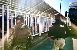 Agentes de la Policía Rodoviaria Federal custodiando a los paraguayos que esperan en la pasarela del Puente de la Amistad recibir el permiso del Gobierno para ingresar al país.