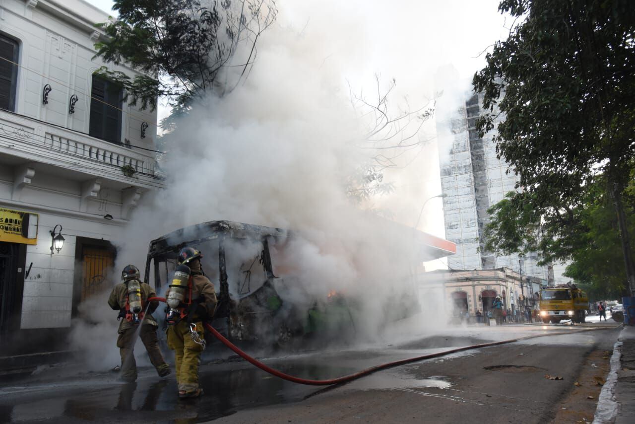 Bomberos voluntarios apagan llamas de bus de la línea 19 incendiado en el centro de Asunción.