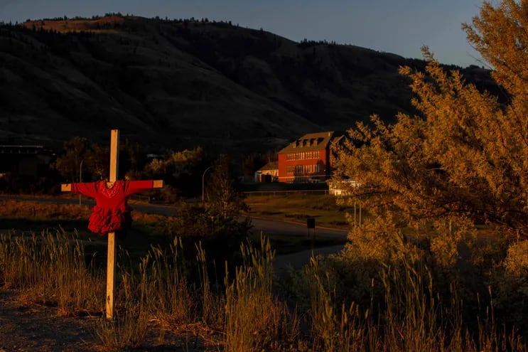 Un atuendo rojo en una cruz al costado de una autopista cerca del sitio del internado para niños indígenas de Kamloops, Canadá.