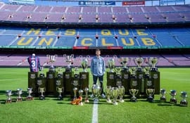 El futbolista Gerard Piqué con los 30 títulos que ganó con el FC Barcelona, en el césped del Camp Nou - FCB