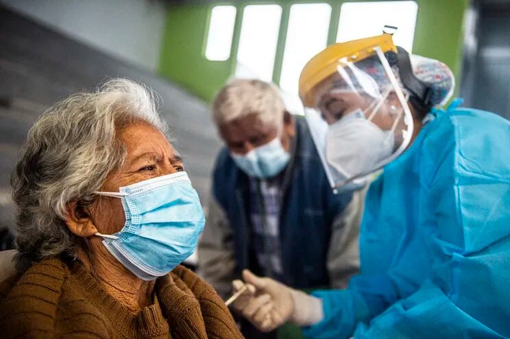 Un trabajador sanitario inocula con una dosis de la vacuna Pfizer-BioNTech contra el COVID-19 a una mujer anciana en Lima.